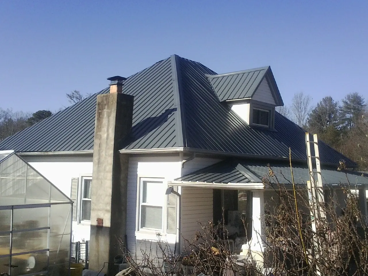 Dark blue standing seam metal roof on a white farmhouse with dormer — Slate & Tile Roof Repair by Roofing Brothers in Shadyside
