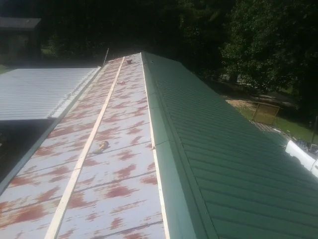 Old rusted panels beside newly installed green metal roofing — Wind Damage Roof Repair by Roofing Brothers in Shadyside