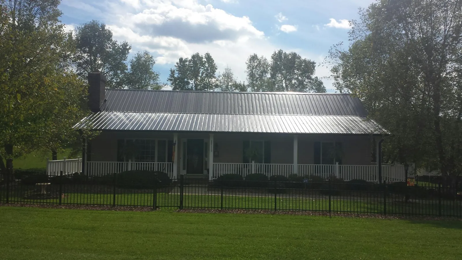 Gray metal roof on a brick ranch with a full width front porch — Gutter Guard Installation work by our crew in Shadyside