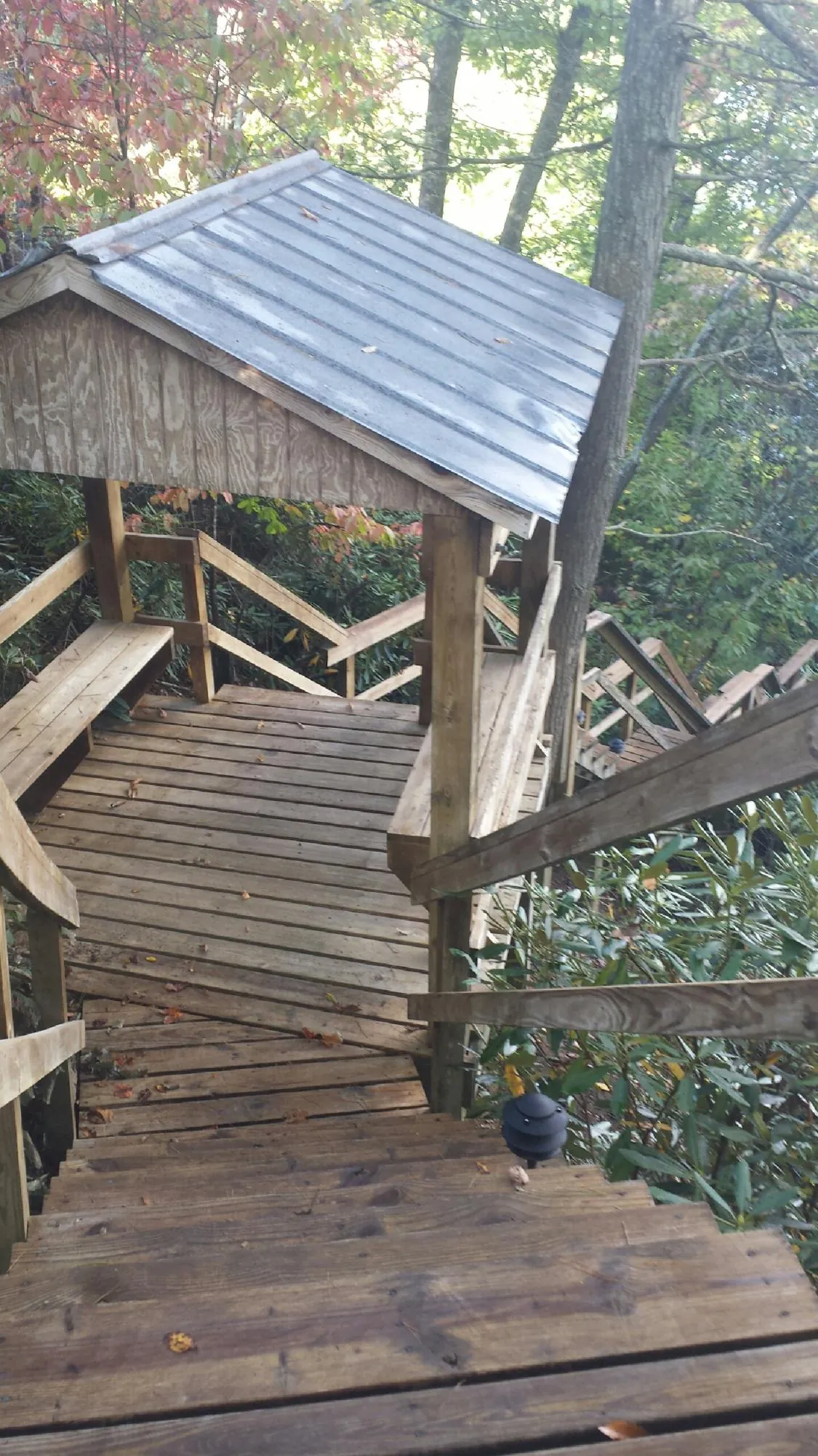 Metal roofed shelter over wooden steps on a wooded walkway — Skylight Repair & Installation work by our crew in Shadyside