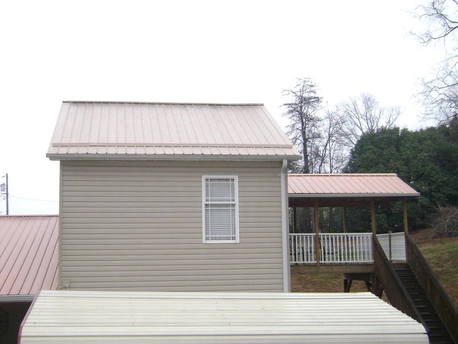 Tan metal roofs on a two story addition and attached porch, from a Roof Replacement job in Shadyside